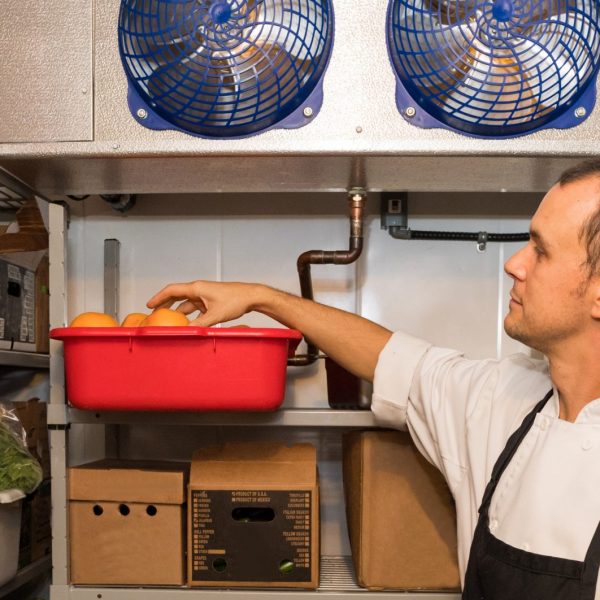 man inside a walk in refrigerator selecting ingredients